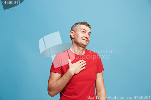 Image of The happy business man standing and smiling against blue background.