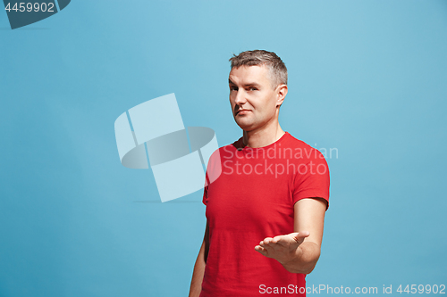 Image of The happy business man standing and smiling against blue background.