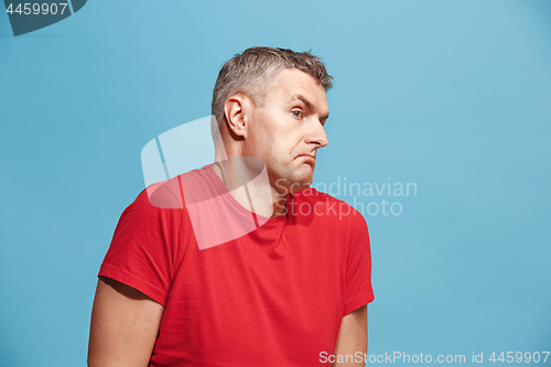 Image of Suspiciont. Doubtful pensive man with thoughtful expression making choice against blue background