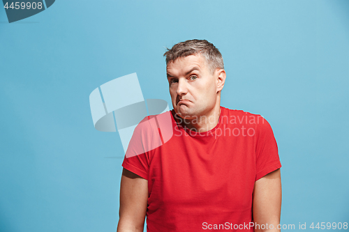 Image of Suspiciont. Doubtful pensive man with thoughtful expression making choice against blue background