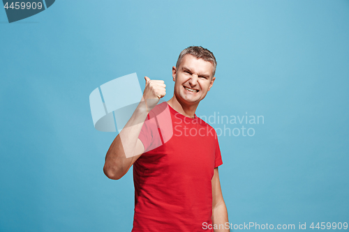 Image of The happy business man standing and smiling against blue background.