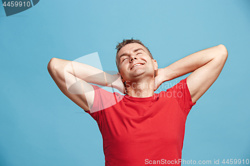 Image of The happy business man standing and smiling against blue background.