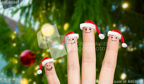 Image of fingers in santa hats over christmas tree