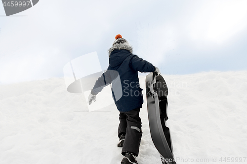 Image of little boy with sled climbing snow hill in winter