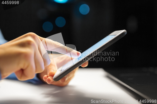 Image of close up of hands with smartphone at night office