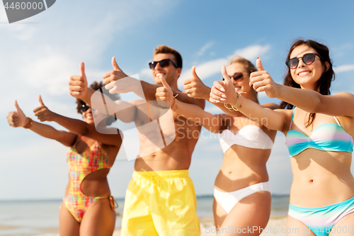 Image of happy friends showing thumbs up on summer beach