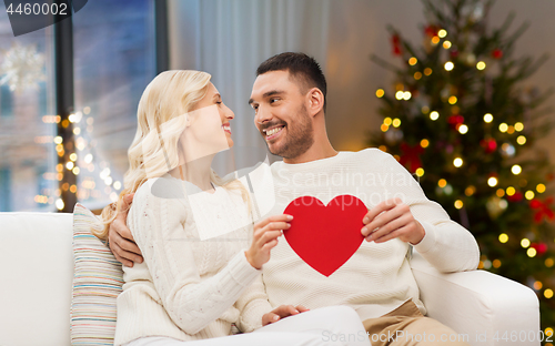 Image of happy couple with red heart at home on christmas