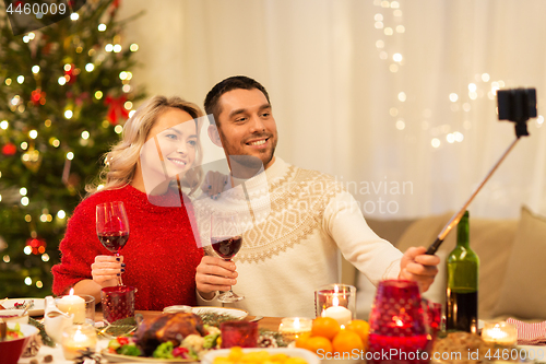 Image of couple taking picture by selfie stick at christmas