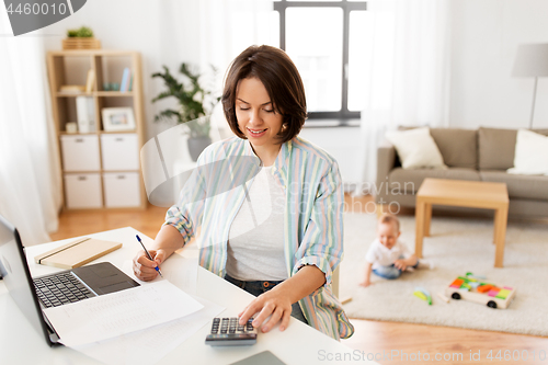 Image of working mother counting on calculator and baby