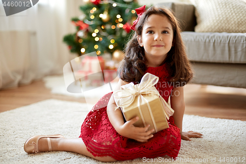 Image of happy girl with christmas gift at home