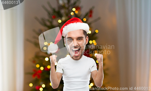 Image of man celebrating victory over christmas tree