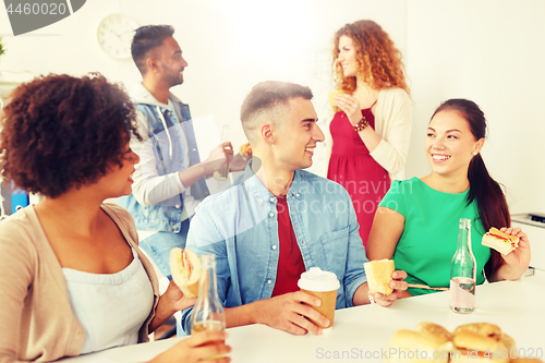 Image of happy friends or team eating at office