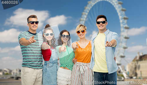 Image of friends pointing at you over ferry wheel in london