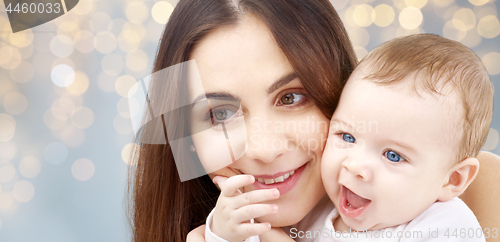 Image of mother with baby over festive lights background