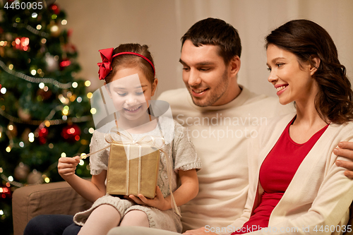 Image of happy family with christmas present at home