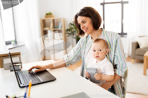 Image of working mother with baby boy and laptop at home