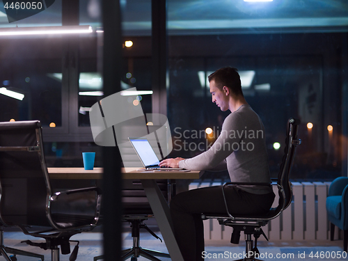 Image of man working on laptop in dark office