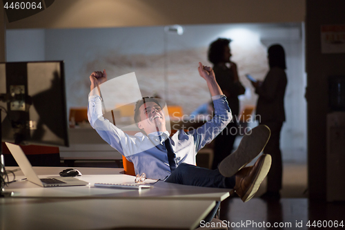 Image of businessman sitting with legs on desk at office