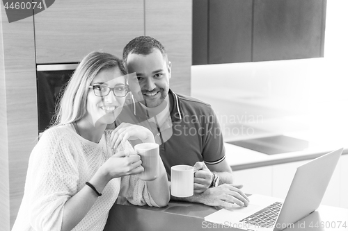 Image of couple drinking coffee and using laptop at home