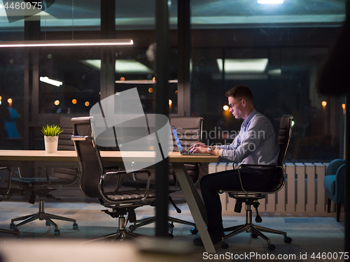 Image of man working on laptop in dark office