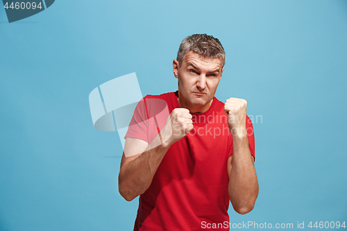 Image of The young emotional angry man screaming on blue studio background