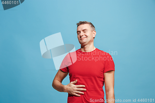 Image of The happy businessman standing and smiling against blue background.