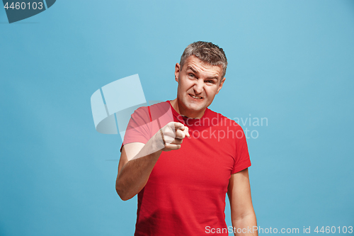 Image of The serious business man pointing to camera, half length closeup portrait on blue background.