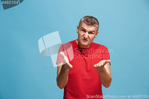 Image of Beautiful male half-length portrait isolated on blue studio backgroud. The young emotional surprised man