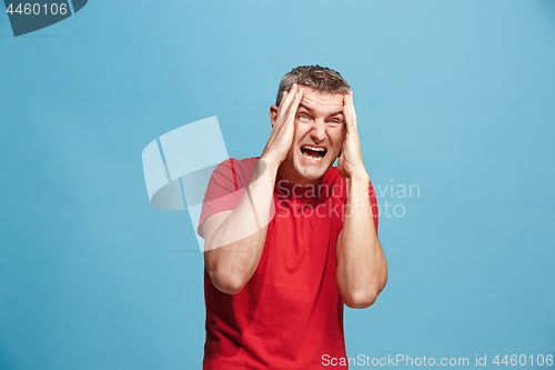 Image of The young emotional angry man screaming on blue studio background