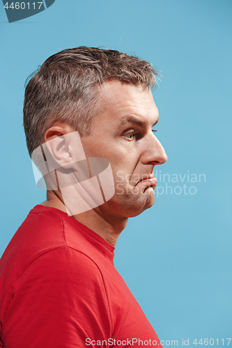 Image of Suspiciont. Doubtful pensive man with thoughtful expression making choice against blue background