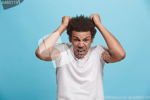 Image of The young emotional angry man screaming on blue studio background