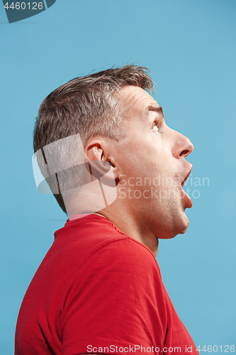 Image of The young attractive man looking suprised isolated on blue