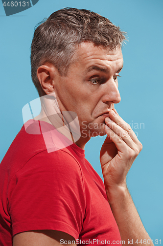 Image of Suspiciont. Doubtful pensive man with thoughtful expression making choice against blue background