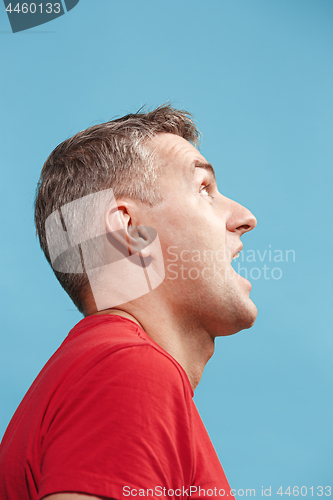 Image of The young attractive man looking suprised isolated on blue