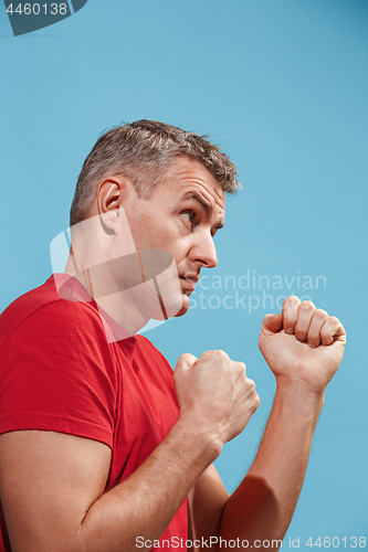 Image of The young emotional angry man screaming on blue studio background