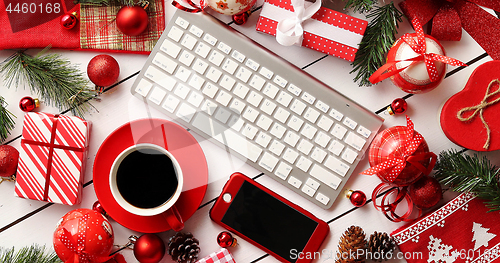 Image of Christmas presents and decorations around gadgets and beverage