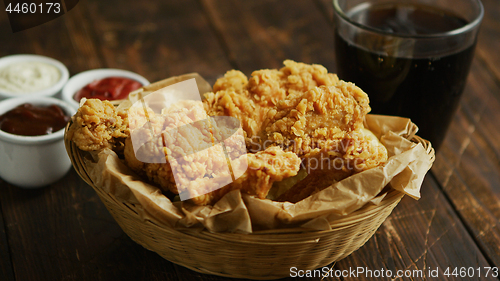 Image of Fried chicken wings near sauces and drink