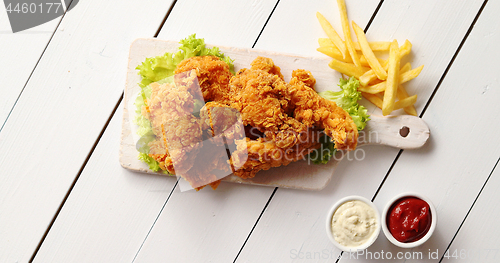 Image of Sauces and French fries near lettuce and chicken wings