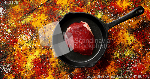 Image of Meat on pan laid on surface with spilt spices