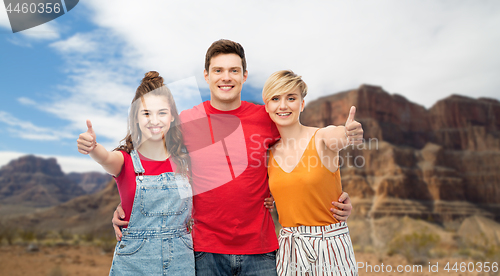 Image of happy friends showing thumbs up and hugging