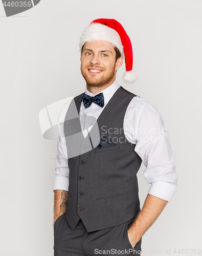 Image of happy man in santa hat and suit at christmas