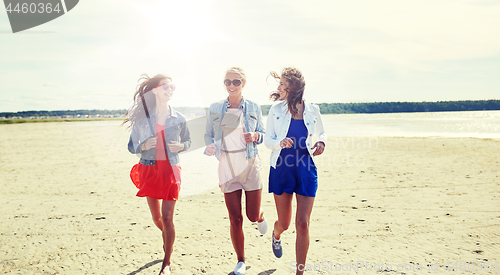 Image of group of smiling women in sunglasses on beach