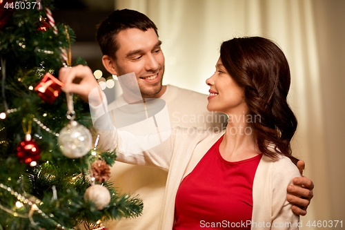 Image of happy couple decorating christmas tree at home