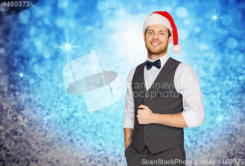Image of happy man in santa hat and suit on christmas