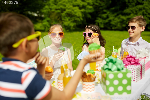 Image of kids eating cupcakes on birthday party in summer