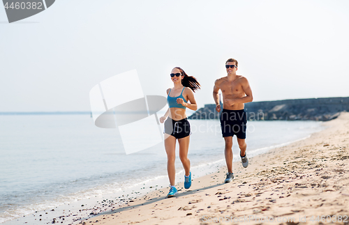 Image of couple in sports clothes running along on beach