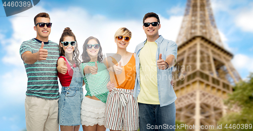 Image of happy friends showing thumbs up over eiffel tower