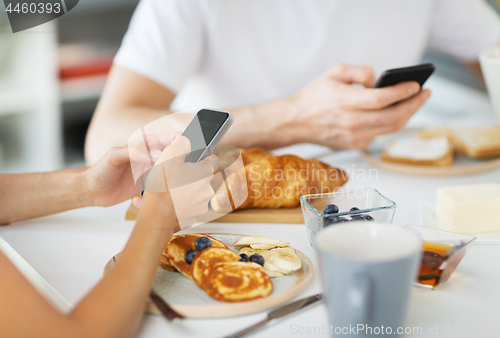 Image of close up of couple with smartphones at breakfast