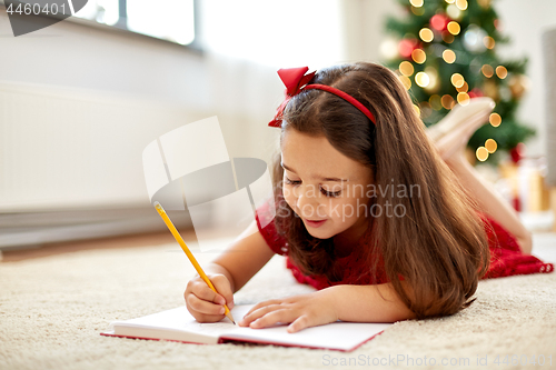 Image of little girl writing christmas wish list at home