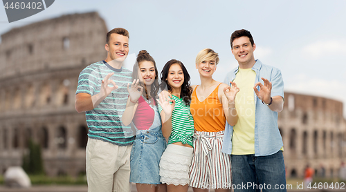 Image of happy friends showing ok hand sign over coliseum